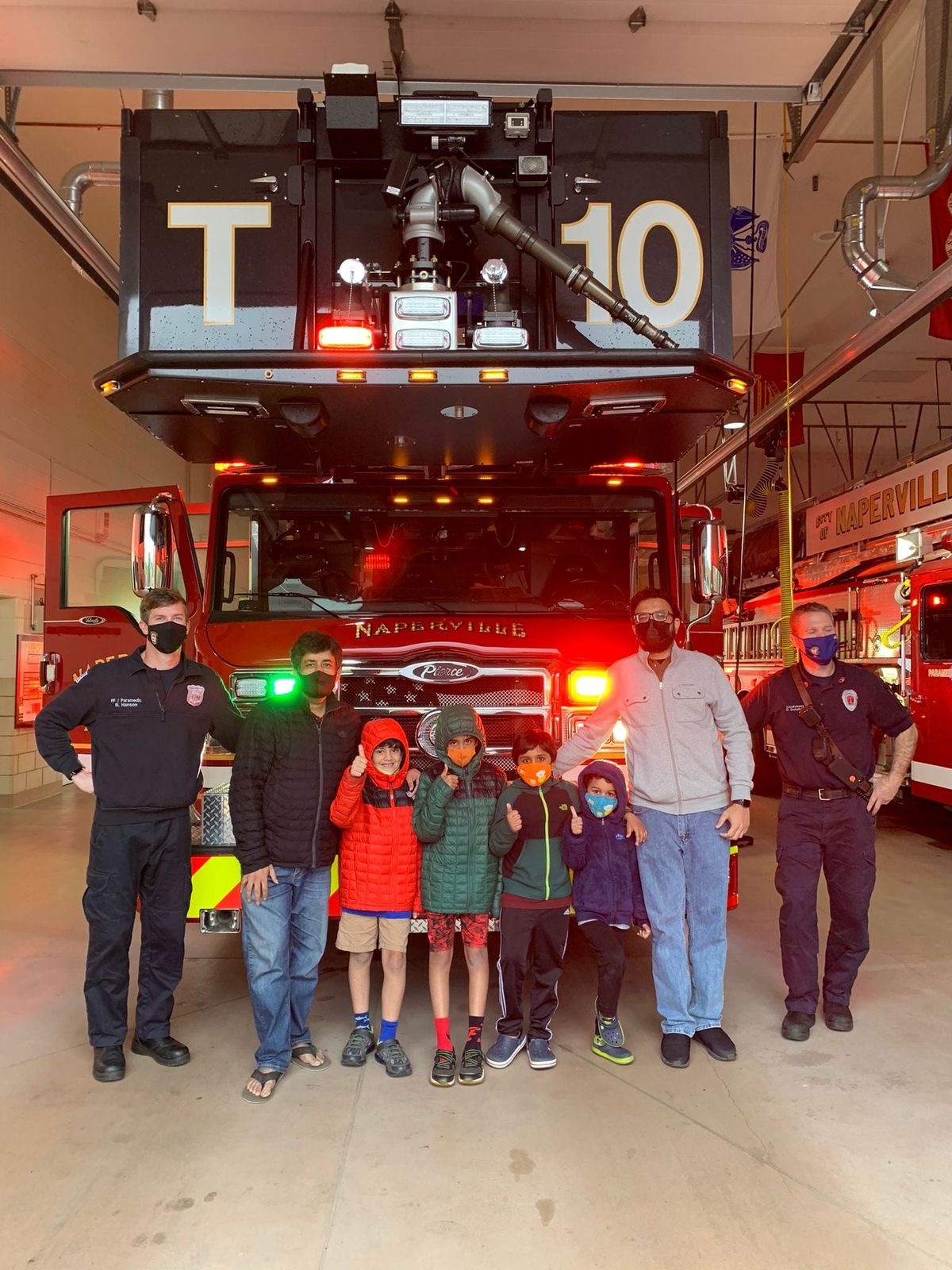 AMAN volunteers and children with firefighters outside a fire station at night