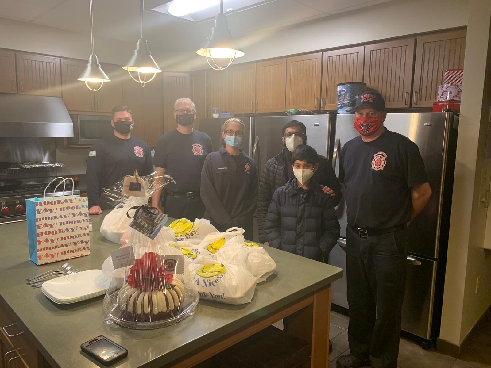 AMAN volunteers with gift bags and food parcels in a fire station kitchen