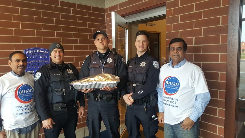AMAN volunteer presenting a turkey to Plainfield police officers